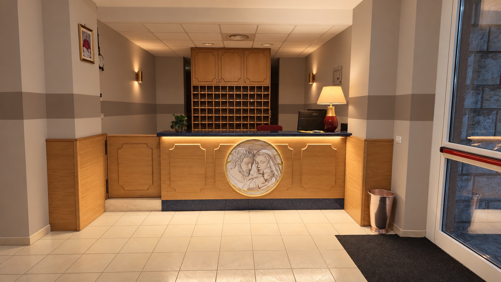 La reception dell’Oasi, con banco in legno illuminato e portachiavi alle spalle